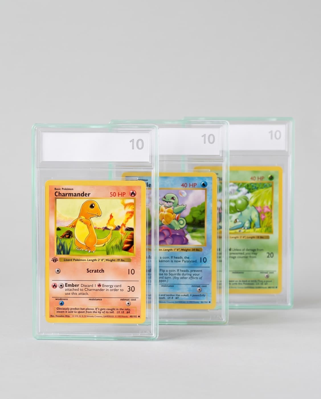 Three Base Set cards, Charmander, Squirtle and Bulbasaur, each in a graded slab labelled 10.